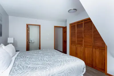 a bedroom with a bed and a wooden closet at 3BR in Sunpath, King Bed, Village Location, Private Patios, Hot Tub and Pool in Whistler
