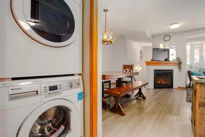 a washer and dryer in a living room with a fireplace at 3BR in Sunpath, King Bed, Village Location, Private Patios, Hot Tub and Pool in Whistler