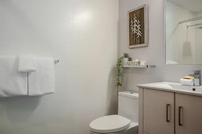 a white bathroom with a toilet and a sink at 3BR in Sunpath, King Bed, Village Location, Private Patios, Hot Tub and Pool in Whistler
