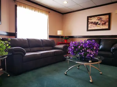 a living room with a leather couch and flowers on a table at MountainView Hotel Merritt in Merritt
