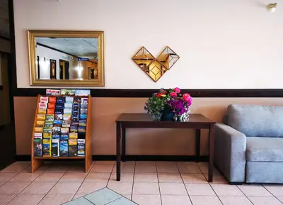 a mirror on a wall next to a table with flowers at MountainView Hotel Merritt in Merritt