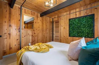 a bedroom with a white bed in a wooden wall at The Matterhorn I HotTub I Ping Pong I Chalk Wall in Fairmont Hot Springs