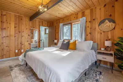 a bedroom with a large white bed in a wooden wall at The Matterhorn I HotTub I Ping Pong I Chalk Wall in Fairmont Hot Springs