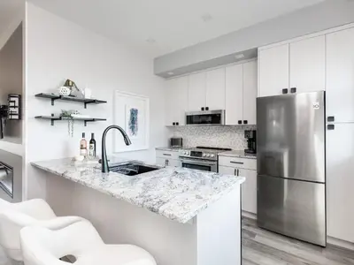 a kitchen with white cabinets and a stainless steel refrigerator at Beautiful 2 bedroom town home in Sunrise Ridge in Parksville