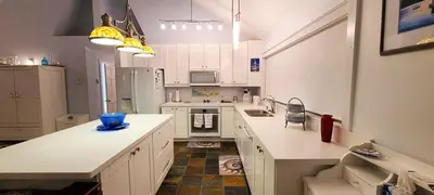 a kitchen with white cabinets and a blue bowl on the counter at The White House in Sechelt