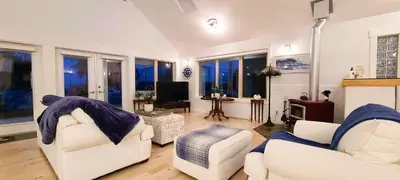 a living room with two white chairs and a tv at The White House in Sechelt