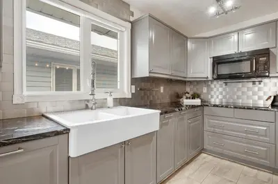 a white kitchen with a sink and a window at Dino Roar I Sleeps 12 I New in Drumheller