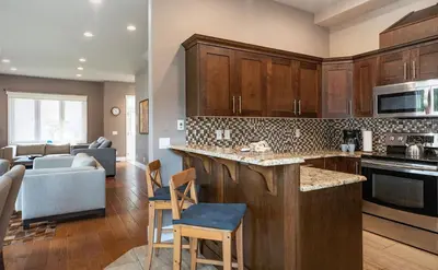 a kitchen with wooden cabinets and a living room at Aspen Lodge by Revelstoke Vacations in Revelstoke