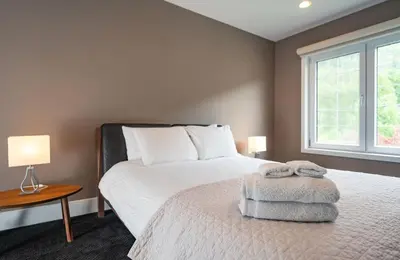a bedroom with a large white bed with a window at Aspen Lodge by Revelstoke Vacations in Revelstoke