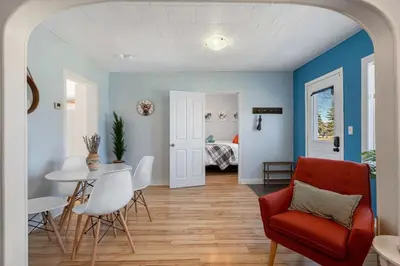 a living room with a red chair and a table at Dino Cave l Walk to Downtown l Fire Pit & BBQ I TV in Drumheller