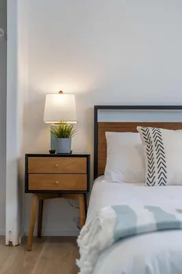 a bedroom with a bed and a nightstand with a lamp at The Hidden Loft I 5-min Walk 2 Beach I DT I 55 TV in Sylvan Lake