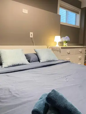 a bedroom with a large bed with blue sheets and pillows at lovely home in Calgary