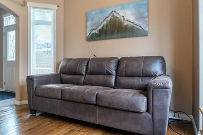 a brown leather couch sitting in a living room at Prairie Oasis I Sleeps 16 l BBQ & Patio l Smart TV in Sylvan Lake