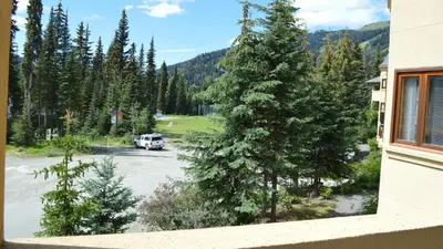 a car parked in a parking lot with trees at Snow Creek Village #49 in Sun Peaks