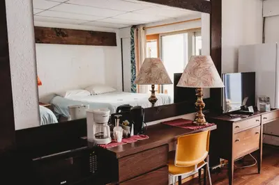 a bedroom with a bed and a desk with a mirror at The Oceanfront Hotel in Sointula