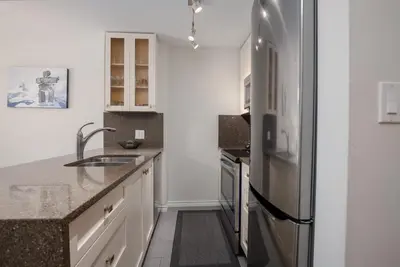 a kitchen with white cabinets and a stainless steel refrigerator at 1BR in The Aspens, King Bed, True Ski In, Ski Out, Hot Tubs and Pool, Ski Valet, Private Balcony in Whistler
