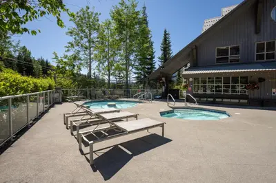 a swimming pool with two benches and a swimming pool at 1BR in The Aspens, King Bed, True Ski In, Ski Out, Hot Tubs and Pool, Ski Valet, Private Balcony in Whistler