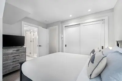 a white bedroom with a bed and a flat screen tv at 2BR in Snowberry, Wood Burning Fireplace, Modern Finishes, Parking, Ski Hill Shuttle in Whistler