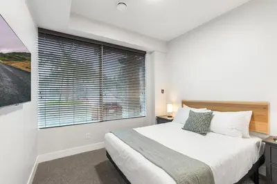 a bedroom with a bed and a large window at Beach Suites in Parksville