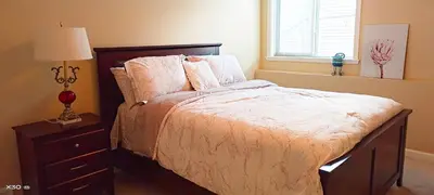 a bedroom with a bed with a dresser and a window at 1 bedroom lake Mountain view in West Kelowna