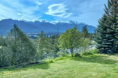 a field with trees and mountains in the background at Pine Ridge, Log Home with Lake View and Backyard in Invermere