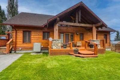 a log cabin with a porch and green grass at Pine Ridge, Log Home with Lake View and Backyard in Invermere