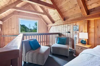 a bedroom with a bed and two chairs in a cabin at Bear Coast, Cabin with Hot Tub, Patio, and Waterview in Ucluelet