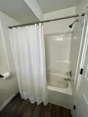 a bathroom with a shower with a white shower curtain at Nakiska, 2 Bed 1 Bath with Mtn Views in Canmore
