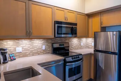 a kitchen with stainless steel appliances and wooden cabinets at Alpenglow Lodge Fika One Bedroom by MVA in Whistler