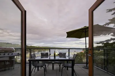 a table with chairs and an umbrella on a balcony at Mariner's Loft - Salt Spring Island in Ganges
