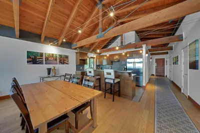 a dining room and kitchen with a wooden table and chairs at Mariner's Loft - Salt Spring Island in Ganges