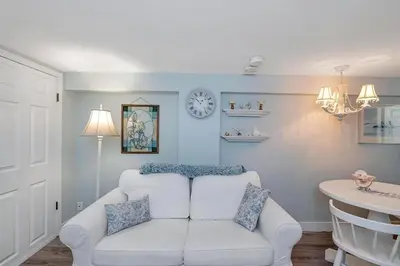 a living room with a white couch and a clock on the wall at Quaint 1 bedroom lower suite in Victoria, BC in Victoria