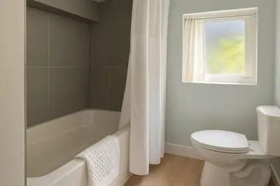 a bathroom with a tub and a toilet and a window at Quaint 1 bedroom lower suite in Victoria, BC in Victoria