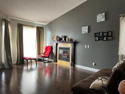 a living room with a fireplace and a red chair at citadle hill house! in Calgary