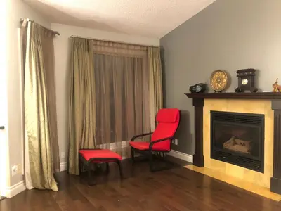 a living room with two red chairs and a fireplace at citadle hill house! in Calgary
