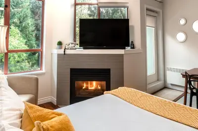 a living room with a fireplace with a flat screen tv at Alpenglow Lodge Large Studio by MVA in Whistler