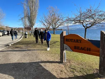 a group of people walking down a sidewalk next to a sign at Peaceful and Spacious Lake View in West Kelowna