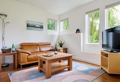 a living room with a couch and a tv at Liahona Guest House in Ucluelet