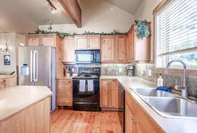 a kitchen with wooden cabinets and a stainless steel refrigerator at Trapper's Lodge - 4 Bd w Great View, Private Hot Tub in Big White