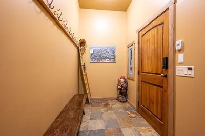 a hallway with a wooden door and a tiled floor at Trapper's Lodge - 4 Bd w Great View, Private Hot Tub in Big White