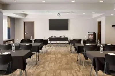 a conference room with tables and chairs and a screen at Microtel Inn & Suites by Wyndham Lloydminster in Lloydminster