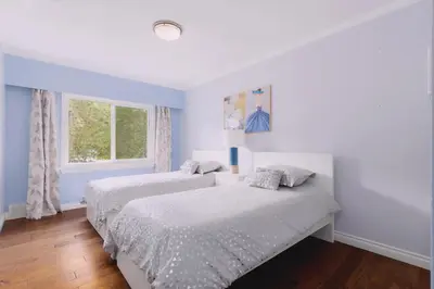 two beds in a bedroom with blue walls and a window at LOVELY 3 bedroom PORT MOODY spacious home 6 people free parking in Port Moody