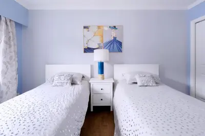 two twin beds in a bedroom with a lamp on a night stand at LOVELY 3 bedroom PORT MOODY spacious home 6 people free parking in Port Moody