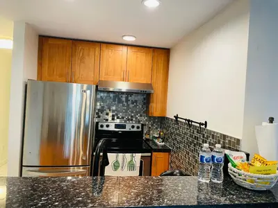 a kitchen with a stainless steel refrigerator and a stove at Adorable 2-Bedroom Basement in Vancouver in Vancouver