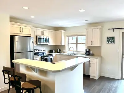 a kitchen with white cabinets and a kitchen island with stools at Perfect base Invermere 3bd townhouse mt views with garage in Invermere