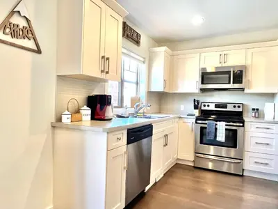 a kitchen with white cabinets and stainless steel appliances at Perfect base Invermere 3bd townhouse mt views with garage in Invermere