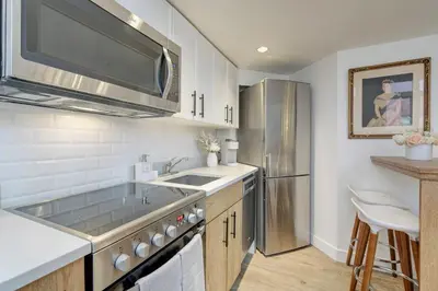 a kitchen with a sink and a stainless steel refrigerator at Victoria's Parliamentary Suite with Private Rooftop Patio & Harbour View in Victoria
