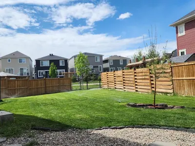 a backyard with a wooden fence and a tree at Guest Suite in Calgary in Calgary