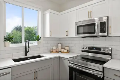 a white kitchen with a sink and a microwave at The Promenade I Patio and BBQ I Fire pit I Sleep 9 in Sylvan Lake