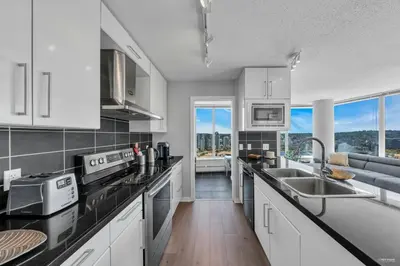 a kitchen with white appliances and a large window at Spacious DT 2-BDR High-rise with view, pool, gym in Vancouver
